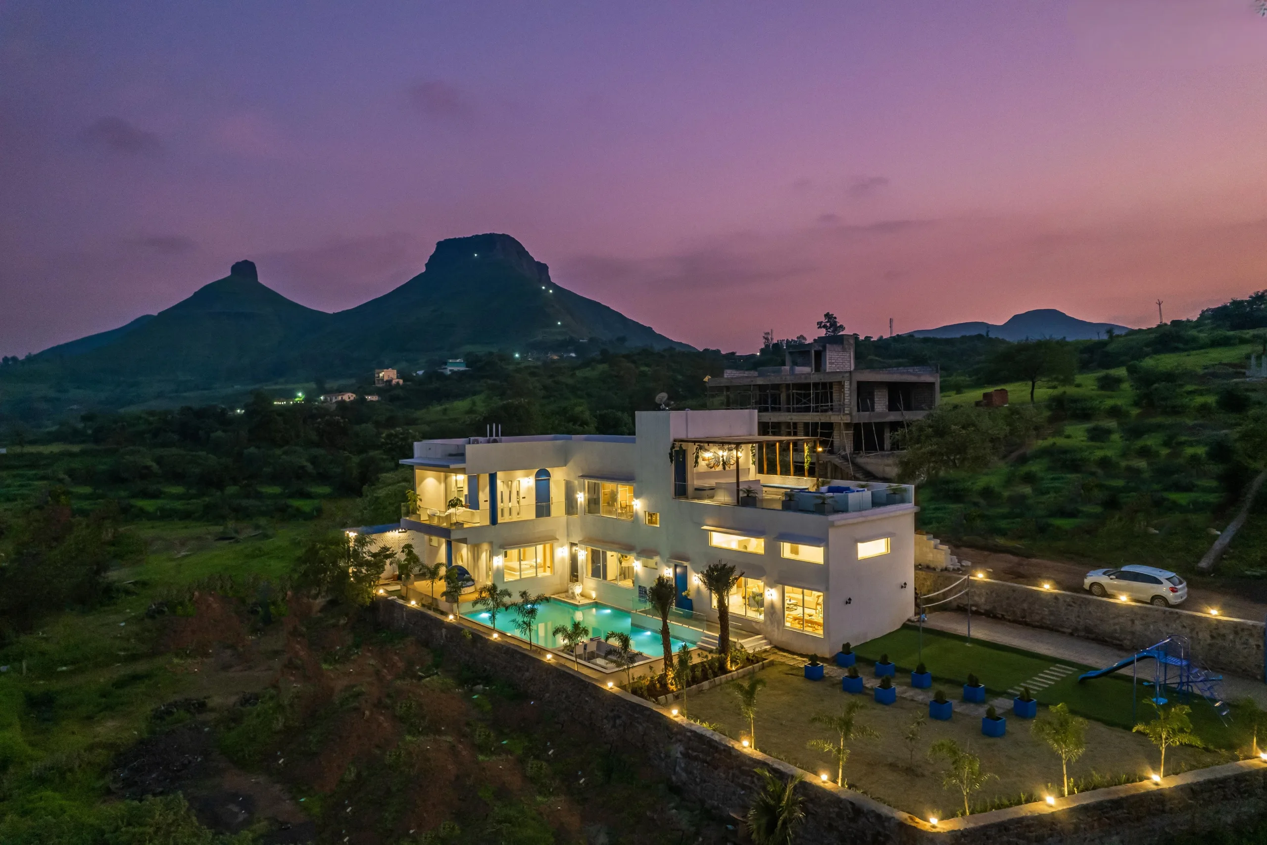 A villa lit at dusk below the peaks of the Western Ghats